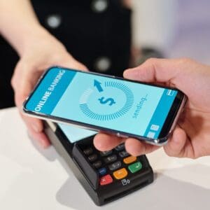 Hand of young man holding smartphone over terminal during contactless payment